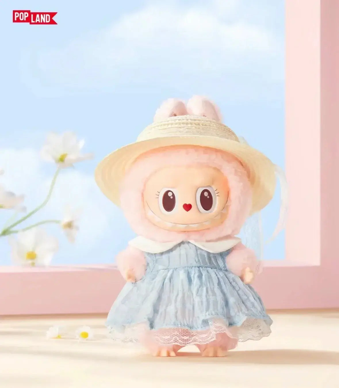 Adorable Pop Land plush figure wearing a bunny hat and blue dress, set against a pastel backdrop with flowers.